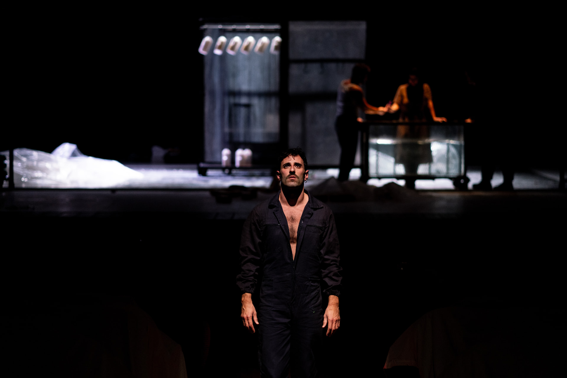 Joele Anastasi in scena al centro di uno spazio teatrale in penombra